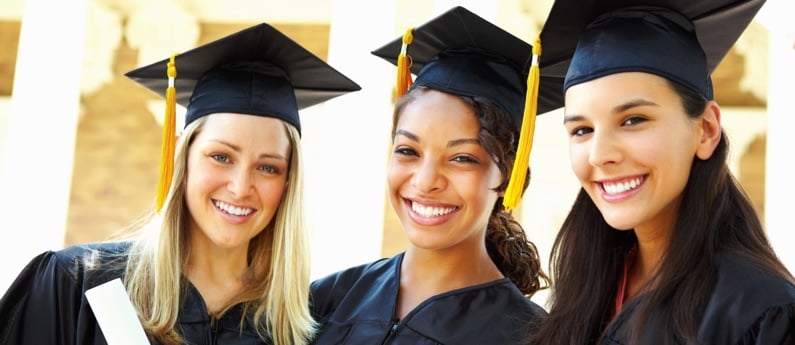 Three First Institute Graduates in full cap and gown.