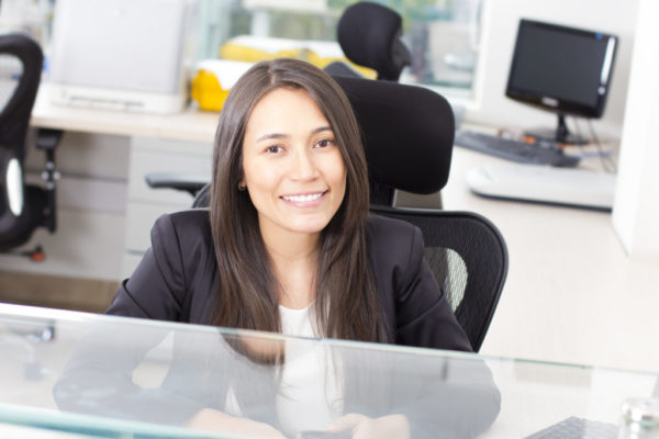 Attractive, smiling female medical assistant sitting behind a counter