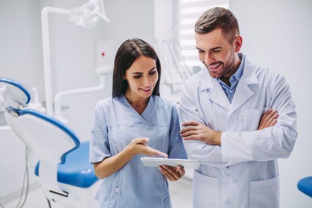 A dentist is talking with a dental assistant